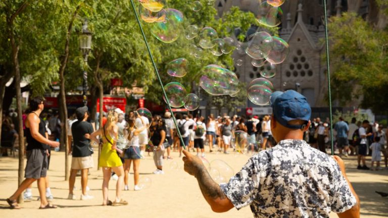 Street artist creates large bubbles amidst a crowd near Sagrada Familia.